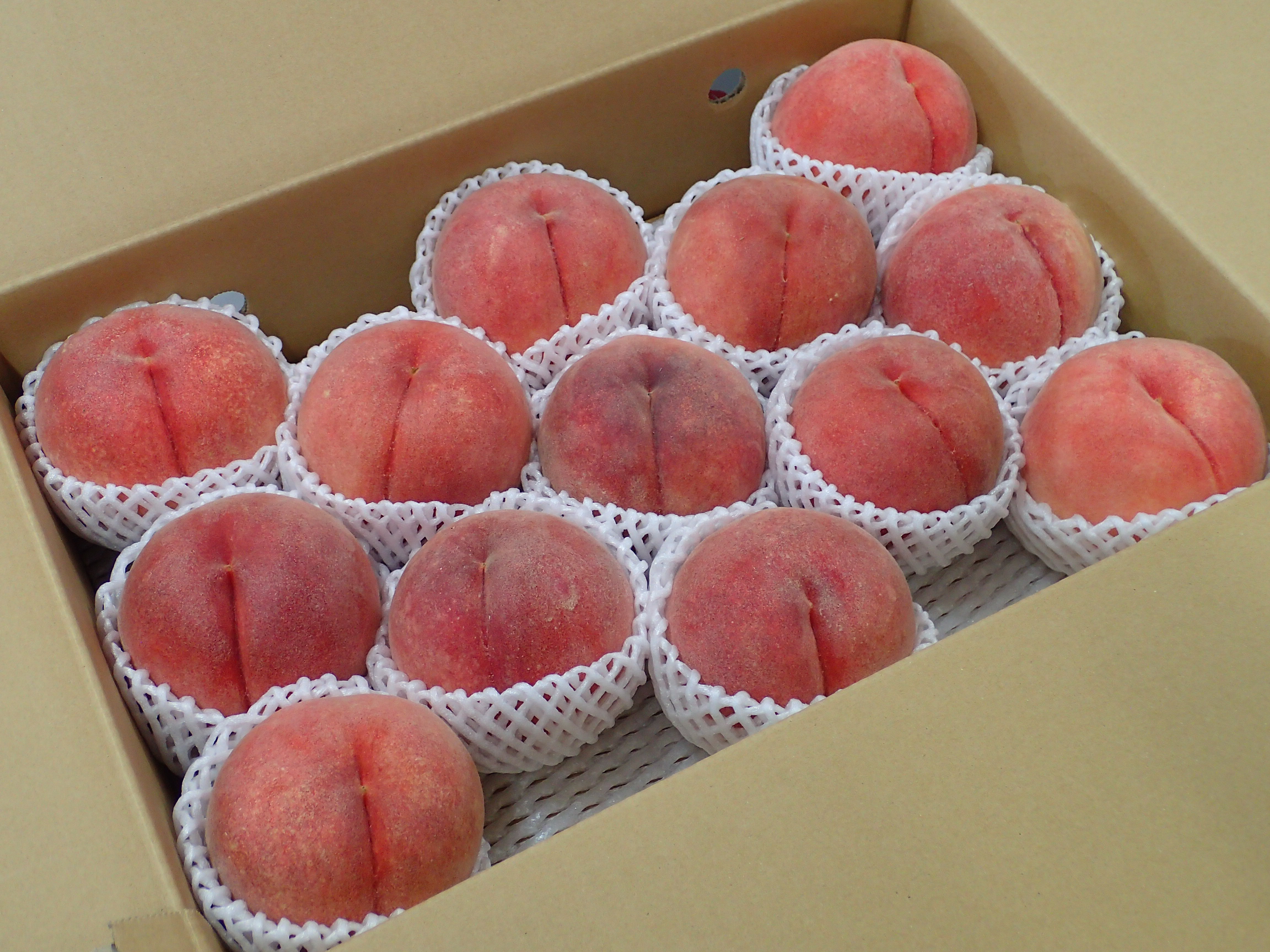 フルーツキャップを被って箱に入った、送られてきたばかりの桃