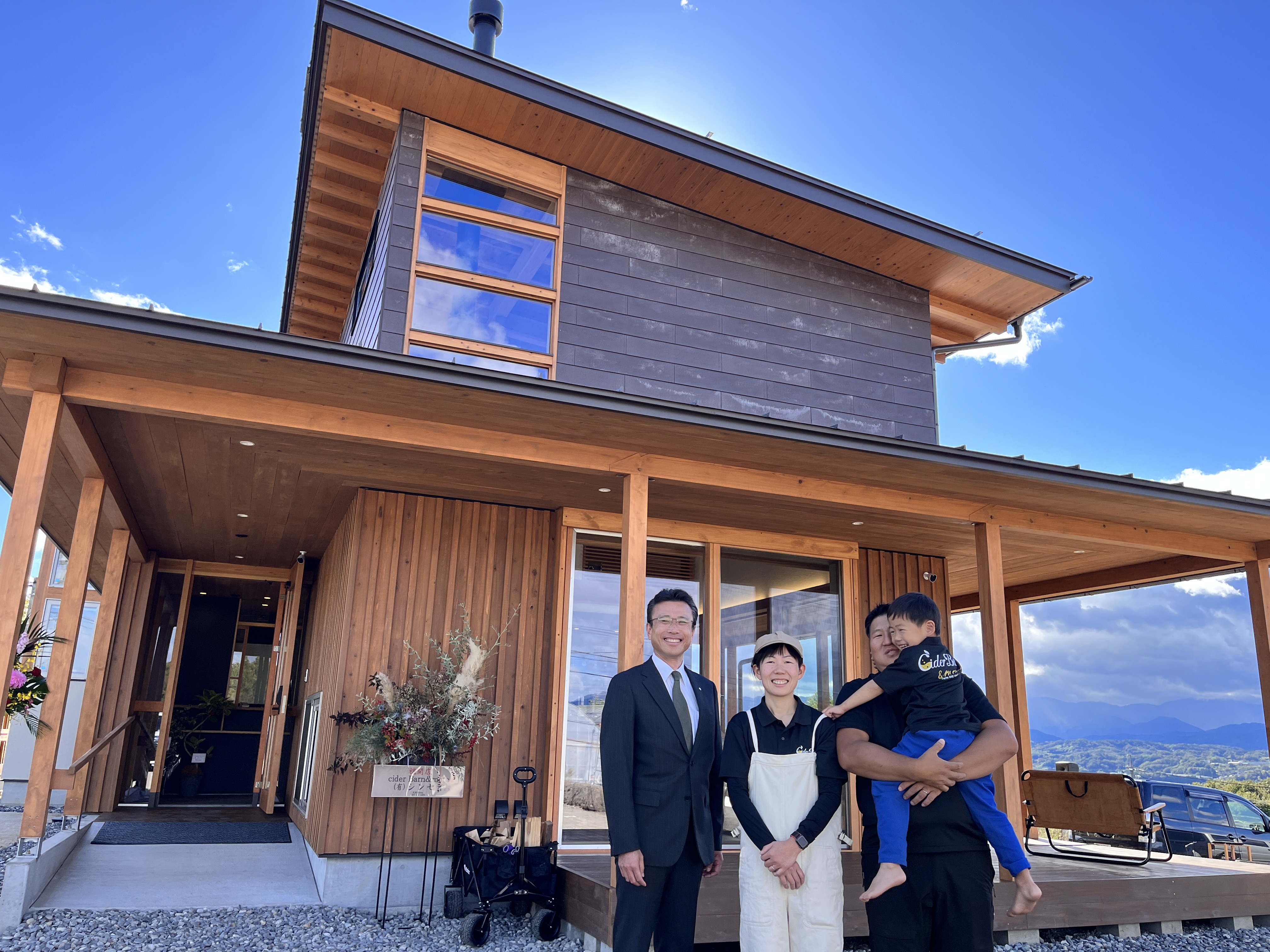 プレオープンした施設の外観と殿倉さん一家と飯田市市長